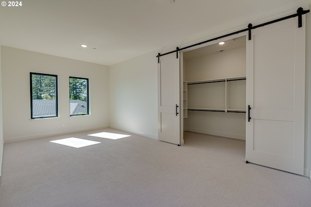 unfurnished bedroom featuring light colored carpet, a spacious closet, and a closet