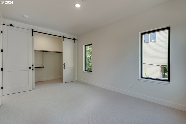 unfurnished bedroom featuring multiple windows, a closet, and light colored carpet