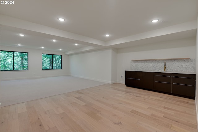 basement with light hardwood / wood-style flooring and sink