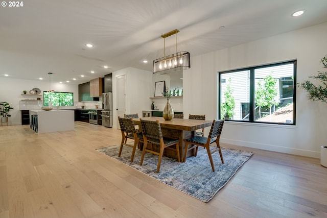 dining space featuring light wood-type flooring and an inviting chandelier