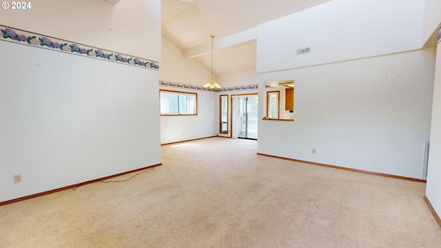 carpeted spare room with ceiling fan with notable chandelier and high vaulted ceiling