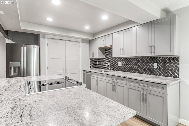 kitchen featuring stainless steel appliances, gray cabinetry, decorative backsplash, recessed lighting, and a sink