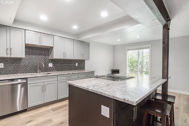 kitchen with sink, dishwasher, light hardwood / wood-style flooring, black electric cooktop, and a center island with sink