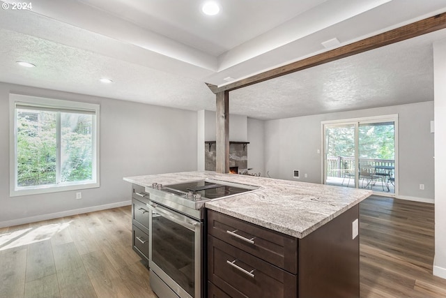 kitchen with wood-type flooring, a textured ceiling, plenty of natural light, and stainless steel electric range