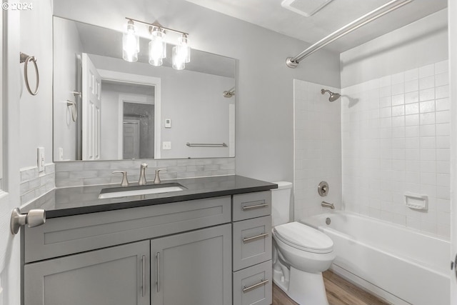 full bathroom with vanity, tiled shower / bath, decorative backsplash, toilet, and wood-type flooring