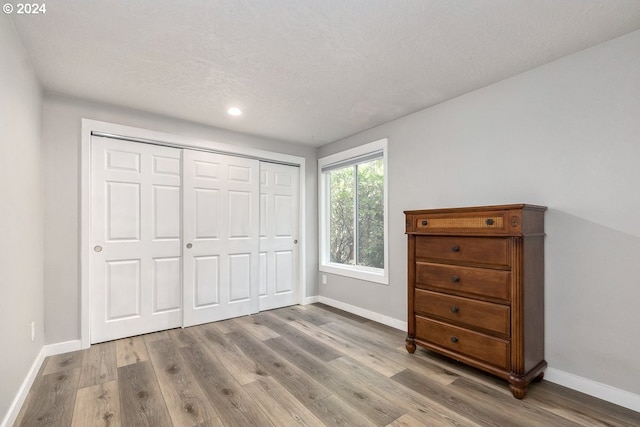 bedroom featuring light hardwood / wood-style floors, a textured ceiling, and a closet