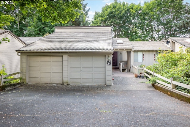 view of front facade featuring a tile roof, fence, and a garage