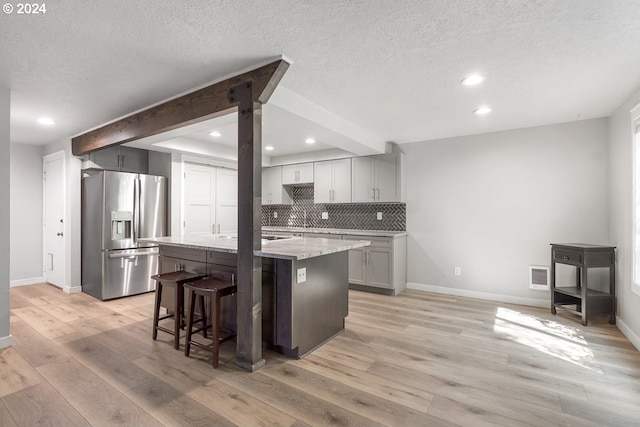 kitchen featuring stainless steel fridge with ice dispenser, baseboards, backsplash, light wood-style floors, and recessed lighting