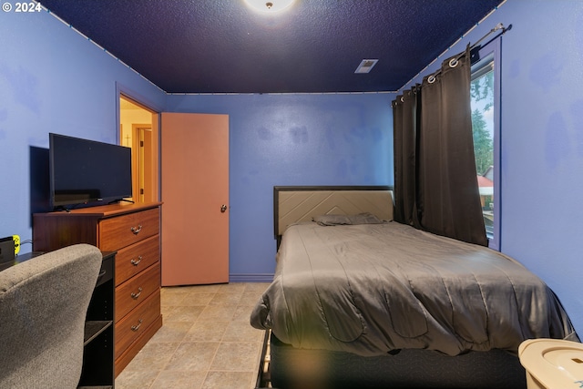 bedroom featuring light tile patterned flooring and a textured ceiling