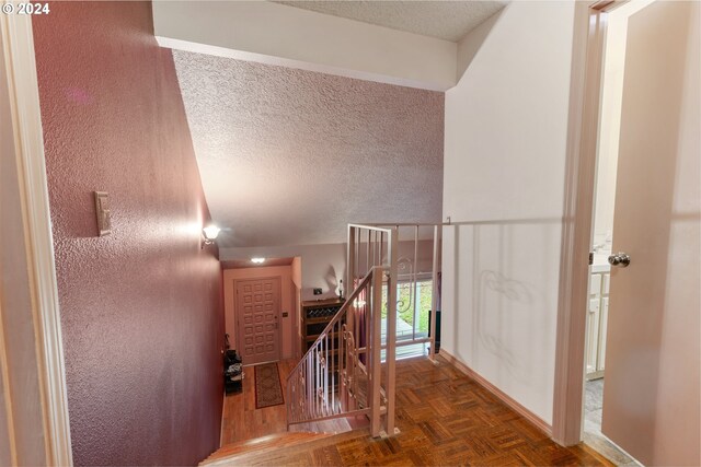 stairway featuring parquet flooring and a textured ceiling