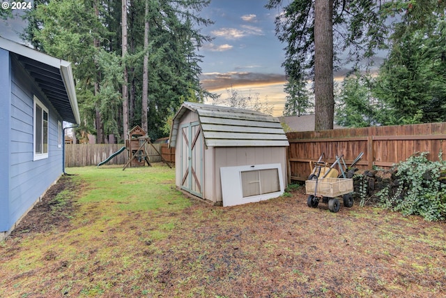 yard at dusk featuring a playground and a shed