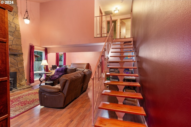 stairs featuring hardwood / wood-style floors, a wood stove, and a high ceiling