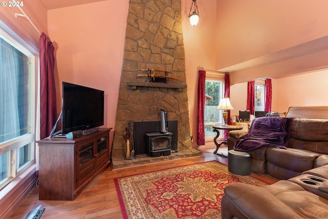 living room featuring light wood-type flooring, a high ceiling, a baseboard radiator, and a wood stove