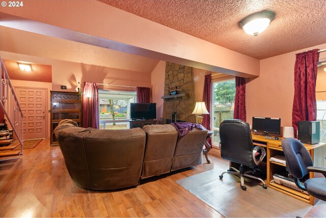 living room with a textured ceiling, light hardwood / wood-style flooring, and vaulted ceiling