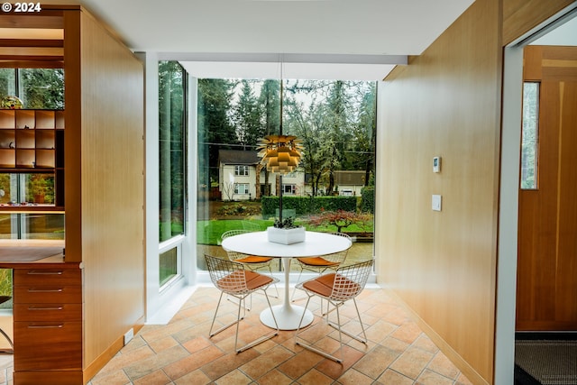 doorway to outside featuring baseboards, a wall of windows, and stone tile flooring