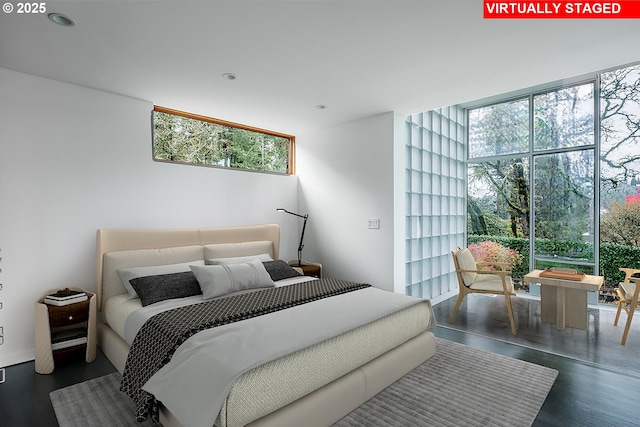 bedroom with a wall of windows and dark hardwood / wood-style flooring