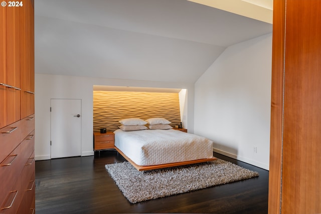 bedroom with vaulted ceiling, baseboards, and dark wood finished floors