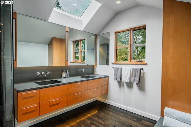full bathroom featuring baseboards, wood finished floors, a sink, and vaulted ceiling with skylight