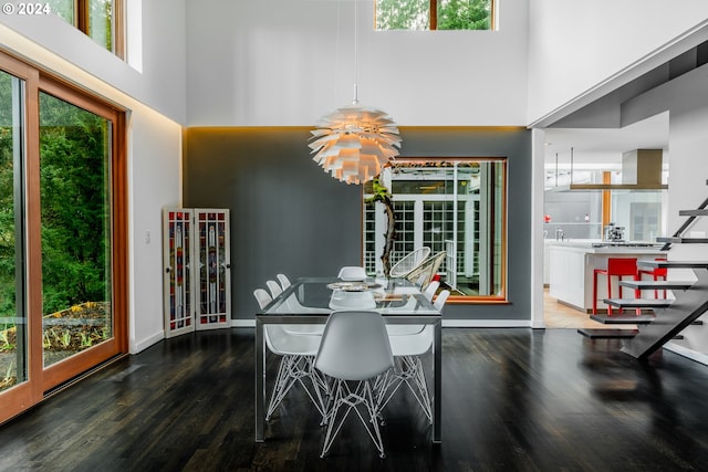 dining area featuring a notable chandelier, a towering ceiling, and dark wood-type flooring