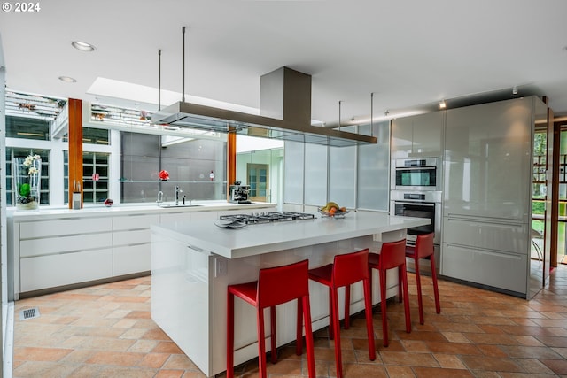 kitchen with white cabinetry, a breakfast bar area, sink, and a kitchen island