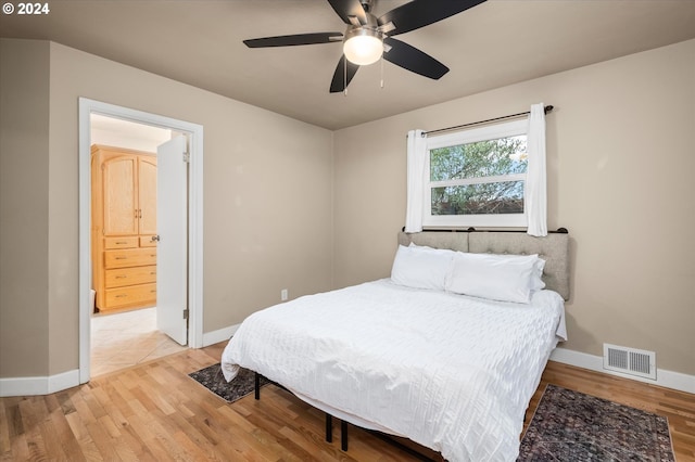 bedroom with ceiling fan, connected bathroom, and light hardwood / wood-style flooring