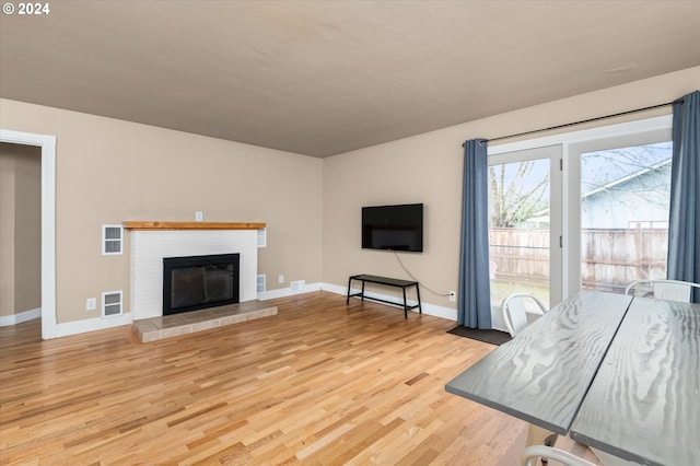 living room featuring light wood-type flooring and a tiled fireplace