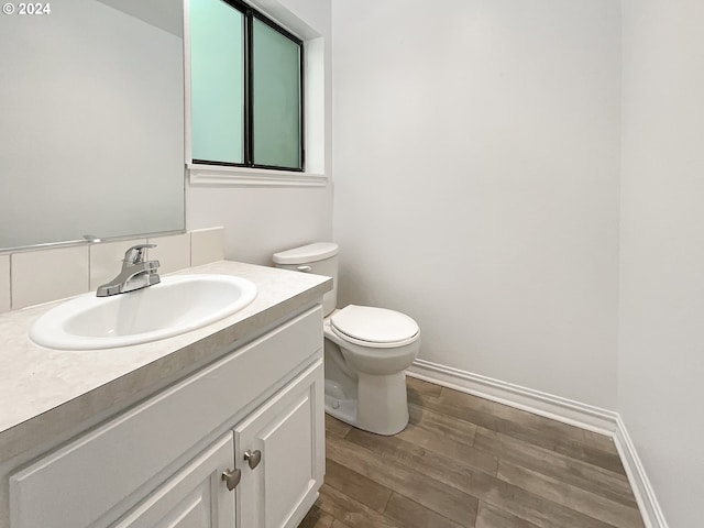 bathroom with hardwood / wood-style flooring, toilet, and vanity