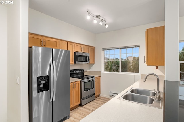 kitchen with sink, light wood-type flooring, stainless steel appliances, and a baseboard heating unit