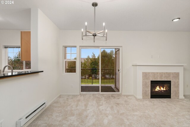 unfurnished living room featuring carpet, a notable chandelier, and a tiled fireplace