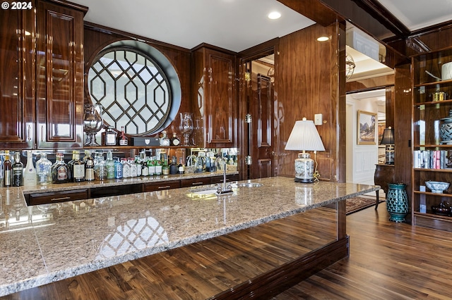 bar with light stone countertops, dark wood-type flooring, and sink