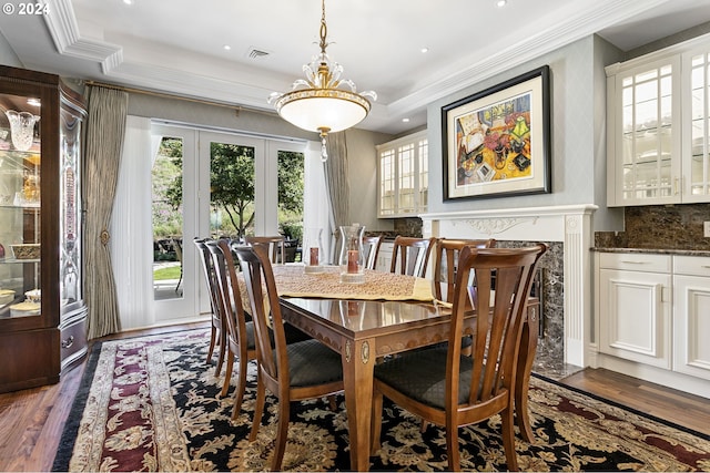 dining space with crown molding, a raised ceiling, dark wood-type flooring, and french doors