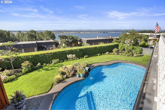 view of swimming pool with a yard and a water view