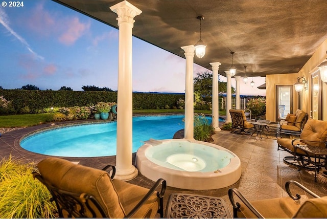 pool at dusk with outdoor lounge area, a patio area, and an in ground hot tub