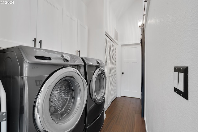 washroom featuring cabinets, dark hardwood / wood-style flooring, and washing machine and clothes dryer