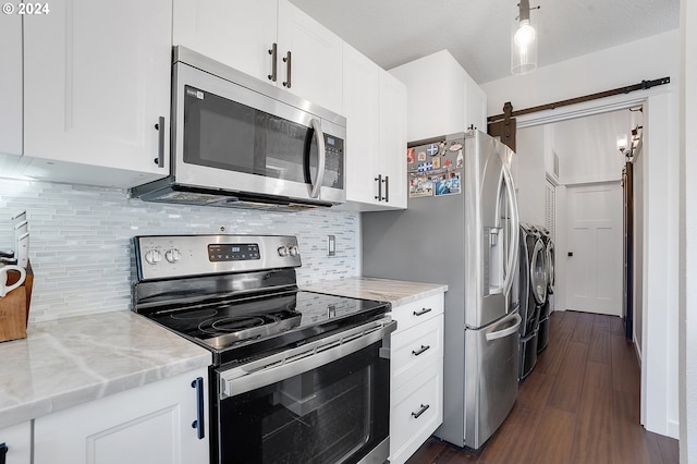 kitchen with dark wood-type flooring, white cabinetry, washer and clothes dryer, appliances with stainless steel finishes, and light stone countertops