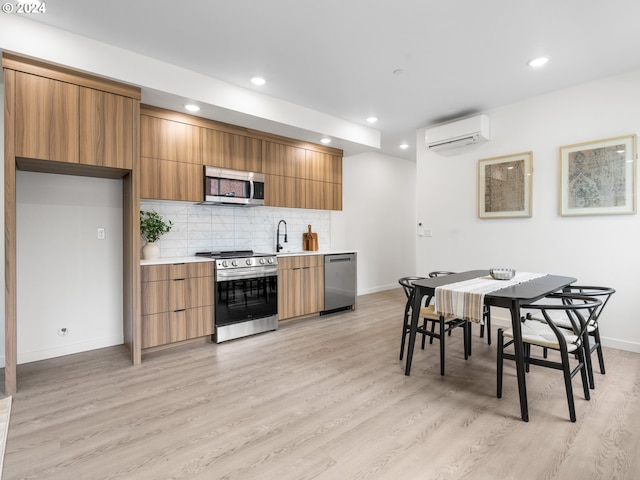 kitchen featuring decorative backsplash, light hardwood / wood-style floors, an AC wall unit, and appliances with stainless steel finishes