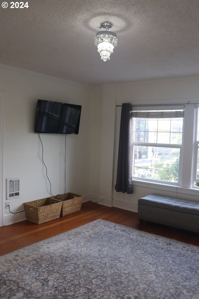 unfurnished living room with heating unit, a chandelier, dark hardwood / wood-style flooring, and a textured ceiling