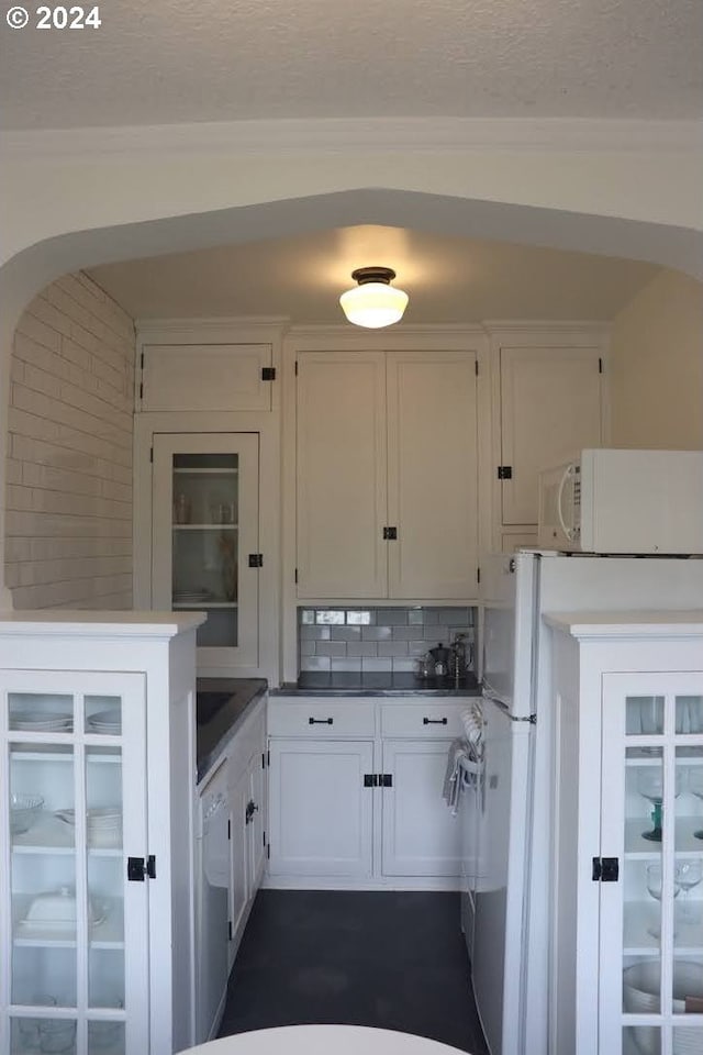 kitchen with white appliances, white cabinets, and backsplash