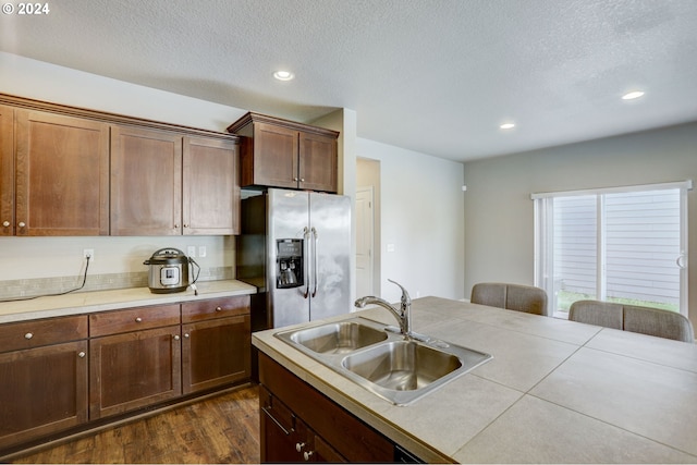 kitchen featuring a textured ceiling, sink, dark wood-type flooring, and stainless steel fridge