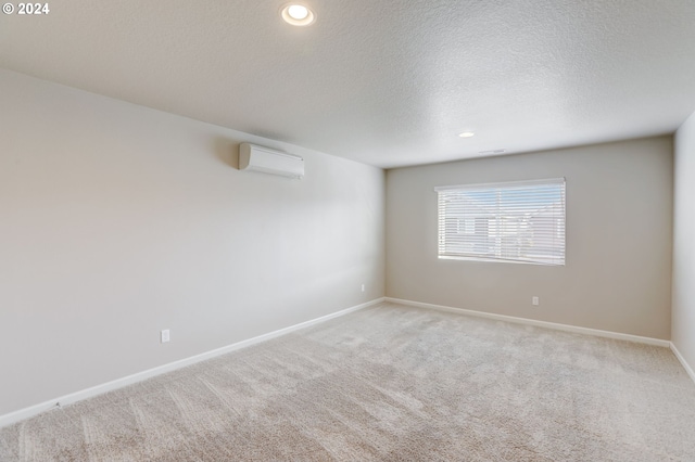 carpeted spare room featuring a textured ceiling and a wall mounted AC