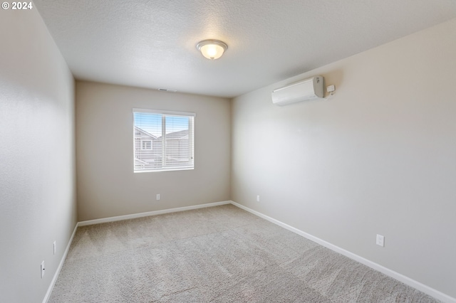 carpeted spare room with a wall unit AC and a textured ceiling