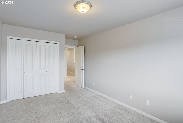 unfurnished bedroom with light colored carpet and a closet