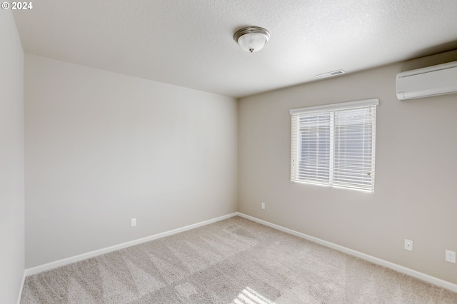 carpeted empty room with a wall unit AC and a textured ceiling