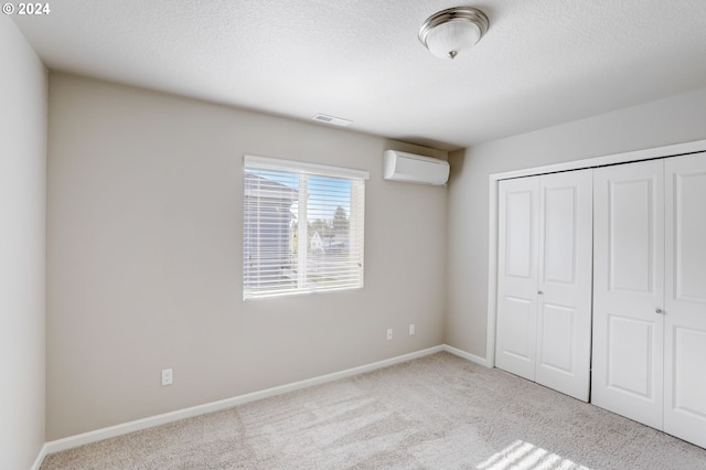 unfurnished bedroom featuring a closet, light carpet, and a wall unit AC