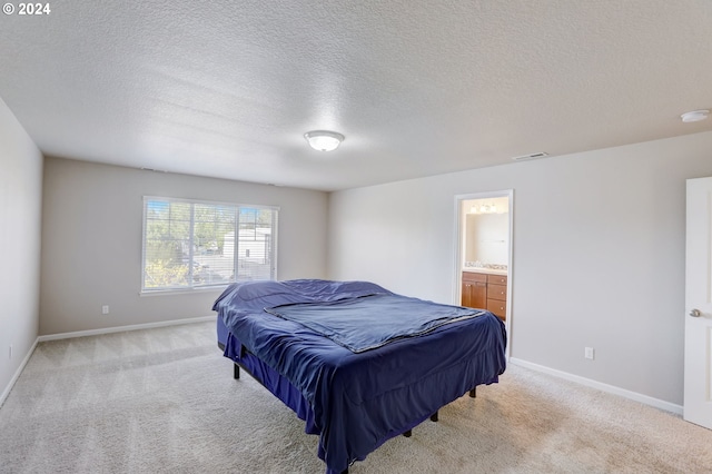 bedroom featuring a textured ceiling, light carpet, and ensuite bathroom