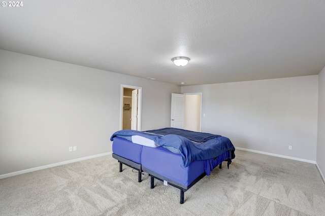 carpeted bedroom with connected bathroom and a textured ceiling