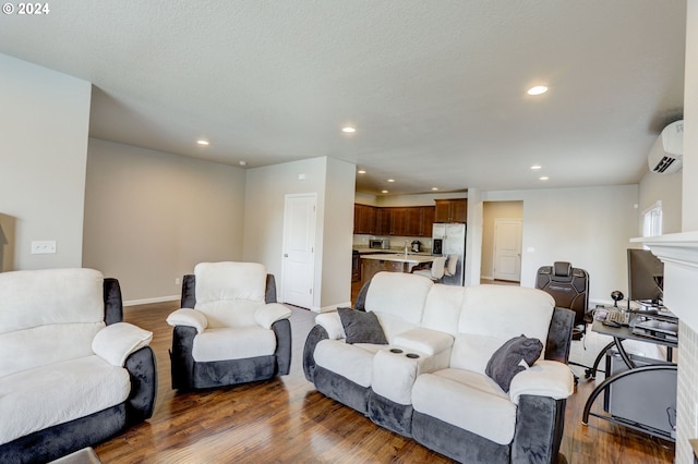 living room with sink, a wall mounted AC, and hardwood / wood-style flooring