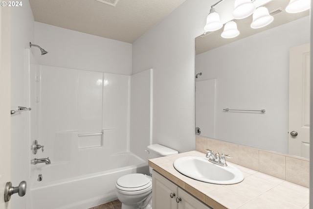 full bathroom with a textured ceiling, shower / bathing tub combination, vanity, and toilet