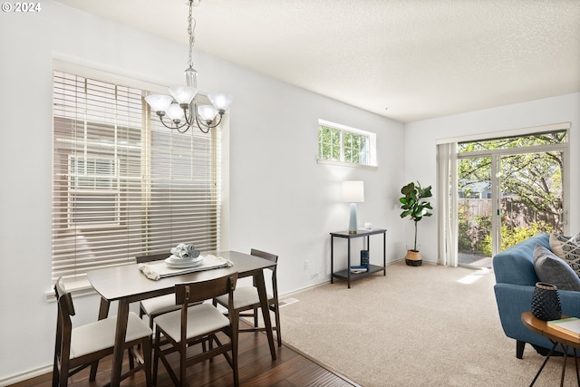 carpeted dining area featuring a chandelier and a textured ceiling