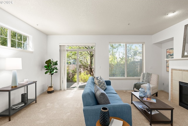 carpeted living room featuring a textured ceiling, a wealth of natural light, and a tiled fireplace